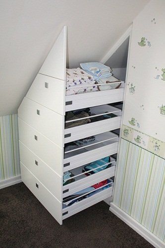 Weißer Einbauschrank unter einer Dachschräge mit ausgezogenen Schubladen voller Kleidung