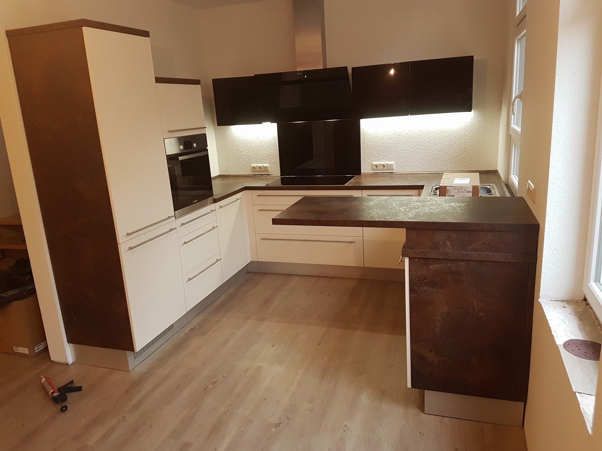 U-förmige Küche mit dunkler Front an Hochschrank und Theke sowie schwarzen Oberschränken