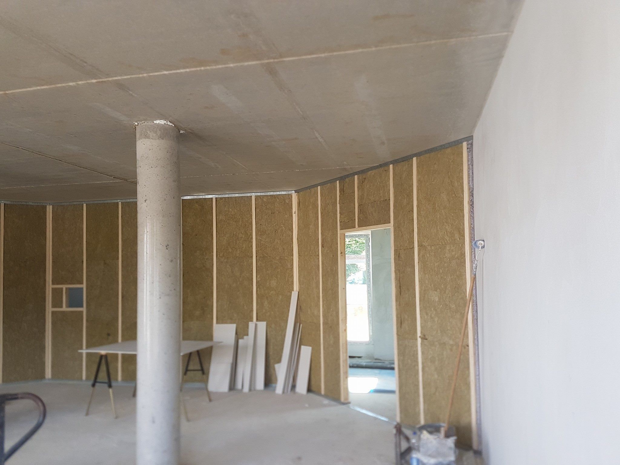Rohbauraum mit Betonstütze, Deckenplatten und Wandständerwerk mit Dämmung